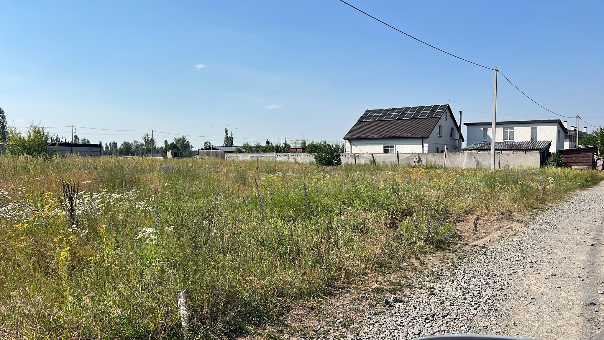 Вільна ділянка праворуч, сусідні будинки та щебенева дорога